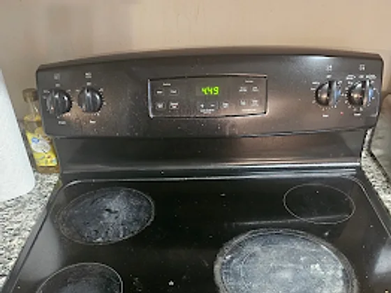 Electric stovetop covered in burnt-on residue before cleaning